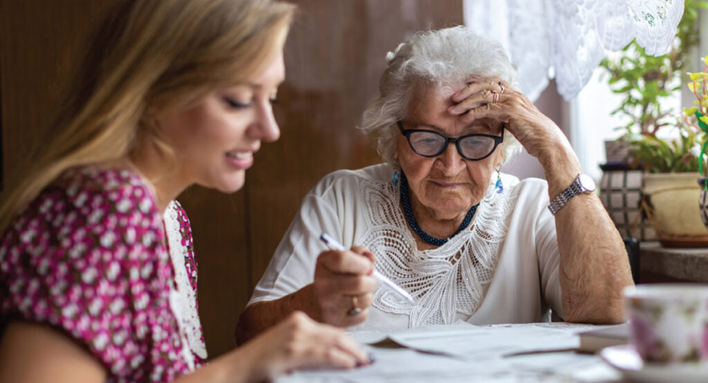 Image of a youg woman helping an elderly woman with paperwork